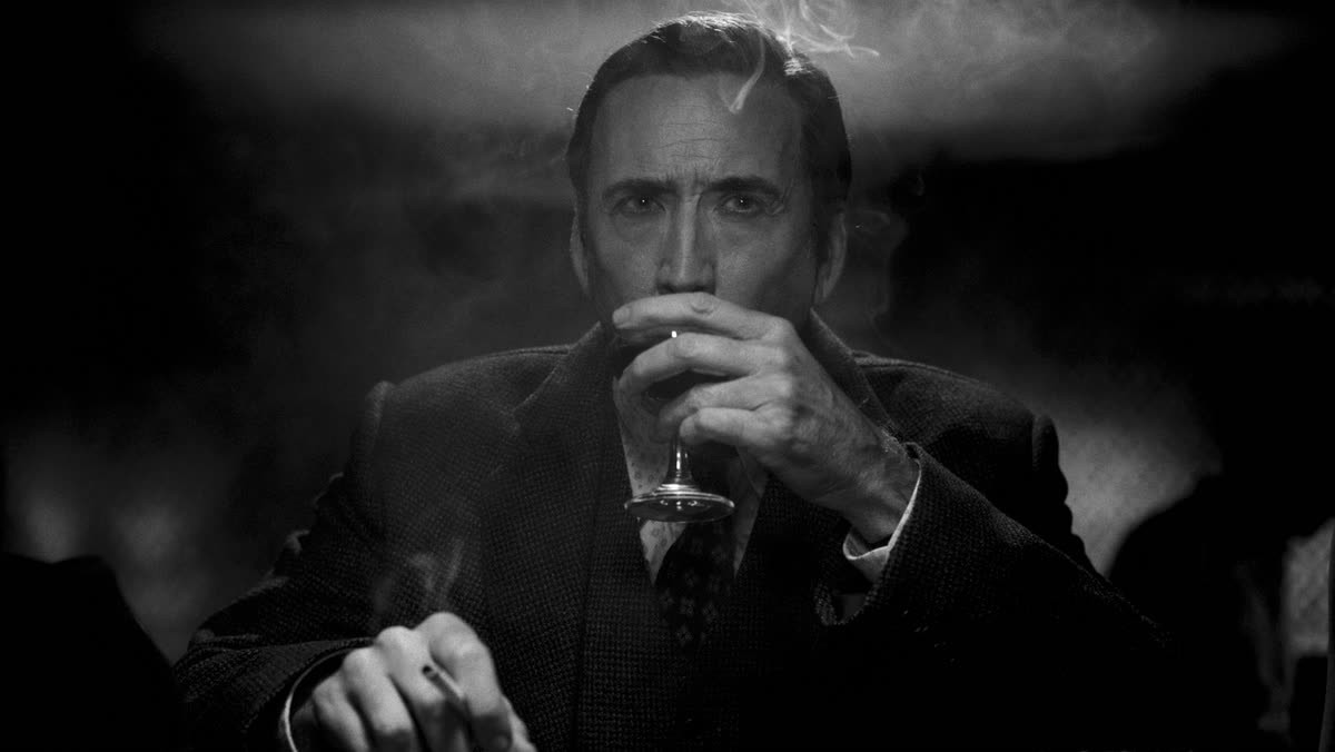 Nicolas Cage as Ben Reilly holds a glass in a smoky club in an official black-and-white Spider-Noir production still.
